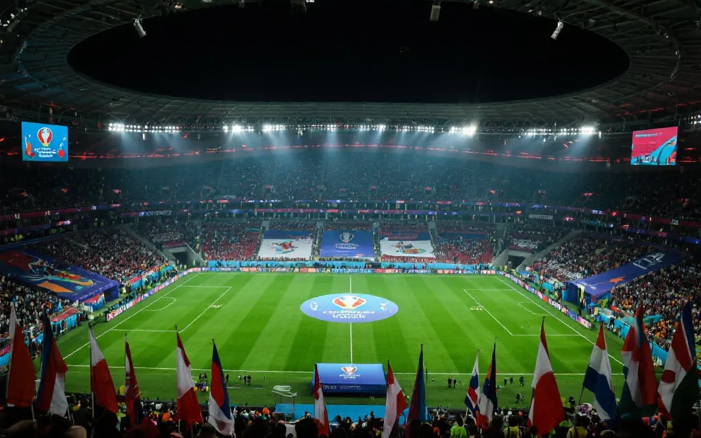 体育场内决赛开赛前的全景，灯光、草坪与看台旗帜形成壮观构图